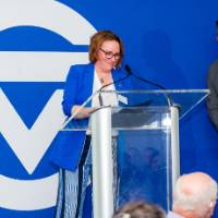 Vice President Kara Van Dam at microphone introducing Dr. Nick Ceglarek, who is to the side waiting to speak to crowd